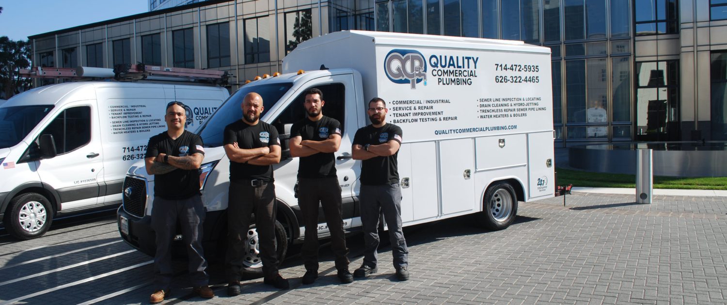 Quality Commercial Plumbing crew in front of a company service van at a commercial property